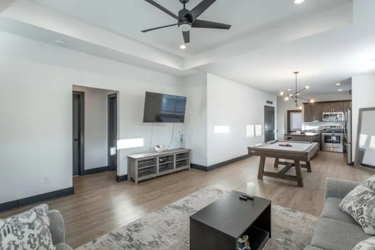 A comfortable, modern living space featuring a large sofa, coffee table, dining table, and a television. The furniture is arranged to encourage both relaxed lounging and communal dining or game nights.